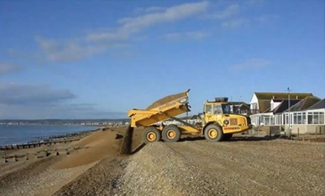 Dumper truck depositing shingle onto a beach as part of shingle recycling works.