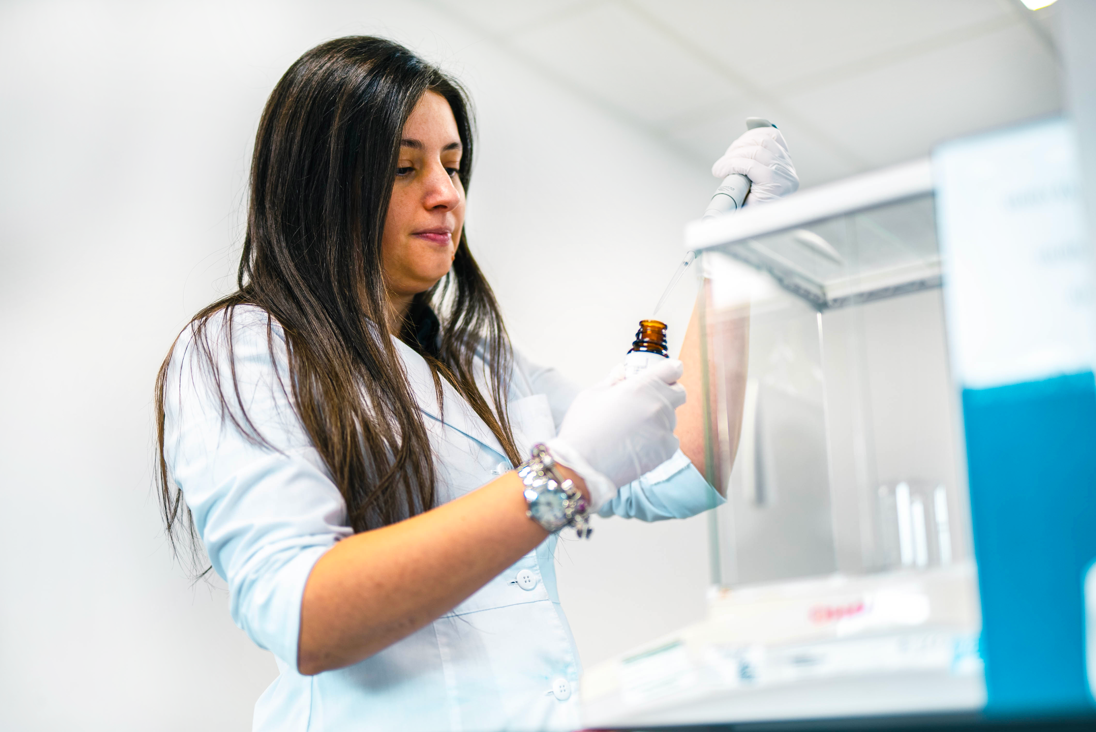 Picture of person in a lab holding a bottle and pipette 