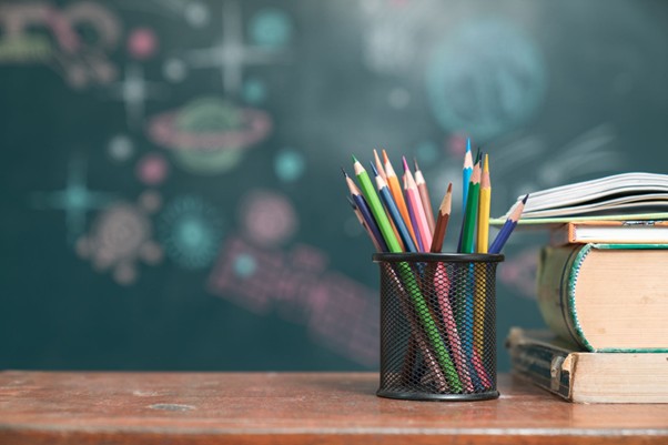 Pot of coloured pencils and a pile of books on a desk