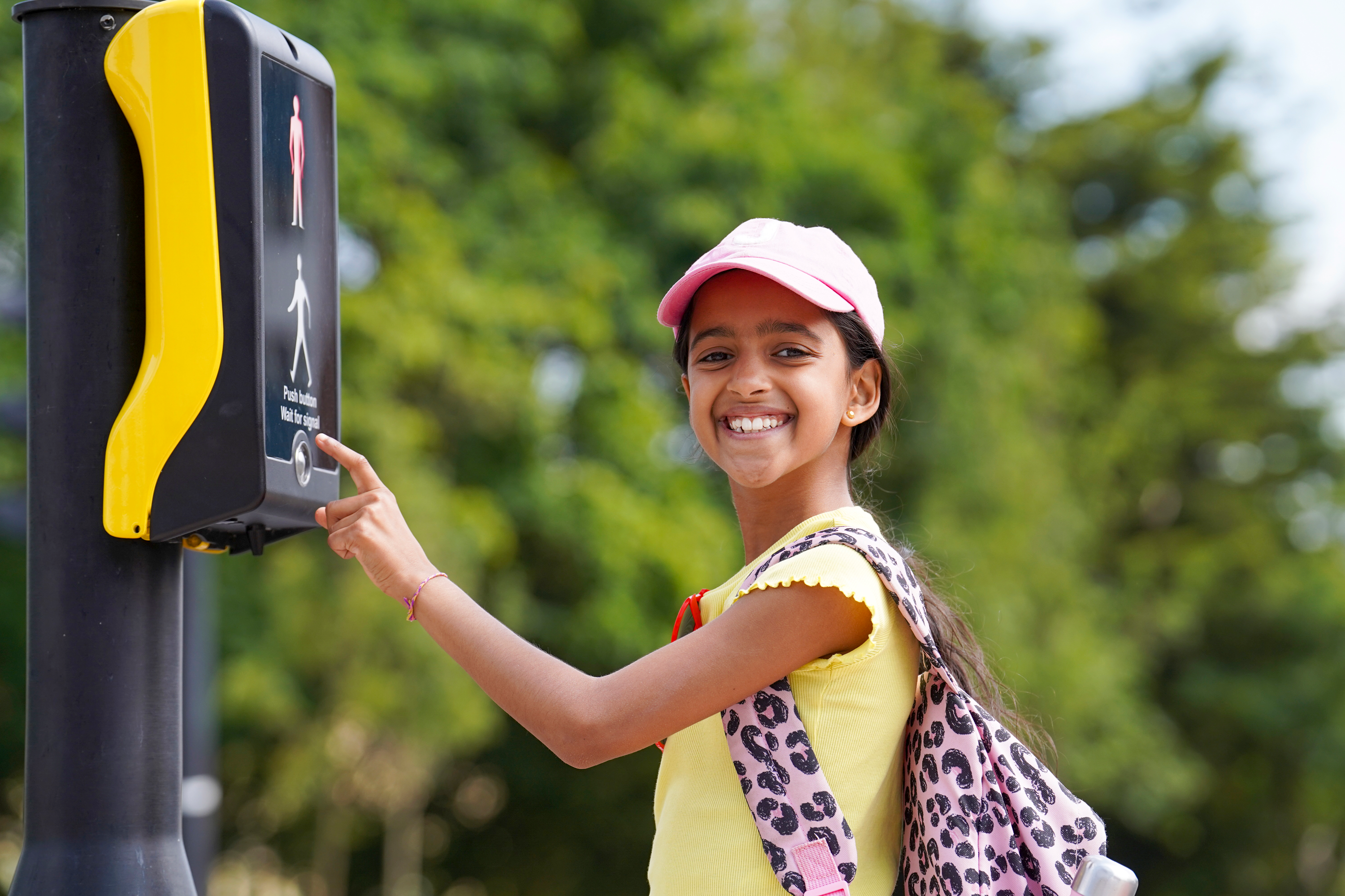 A photograph of a child pushing the button at a pedestrian crossing