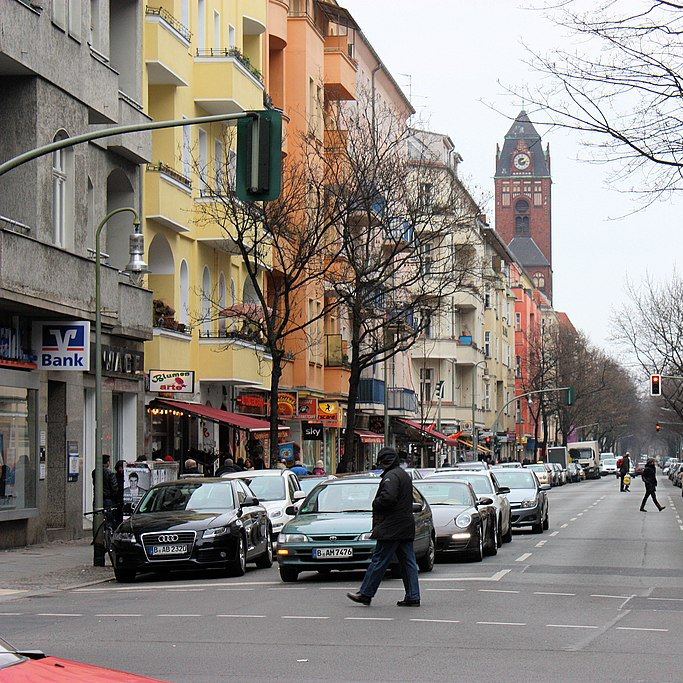 A street scene showing a road with a person crossing at a red light.