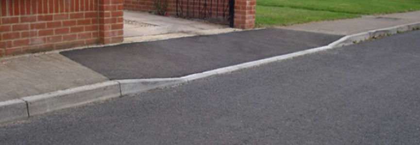 Image shows a crossing in front of a driveway where the pavement continues across the driveway but the kerb drops to allow access for vehicles.