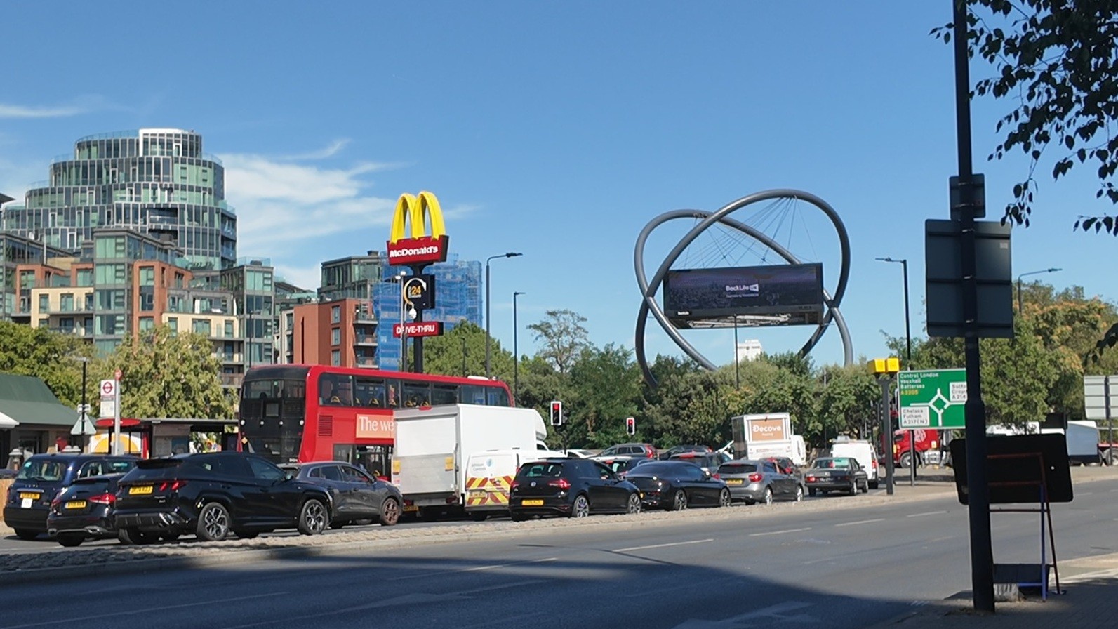 Swandon Way facing the busy gyratory with cars, a red bus and modern buildings near a McDonald's and large roadside sculpture