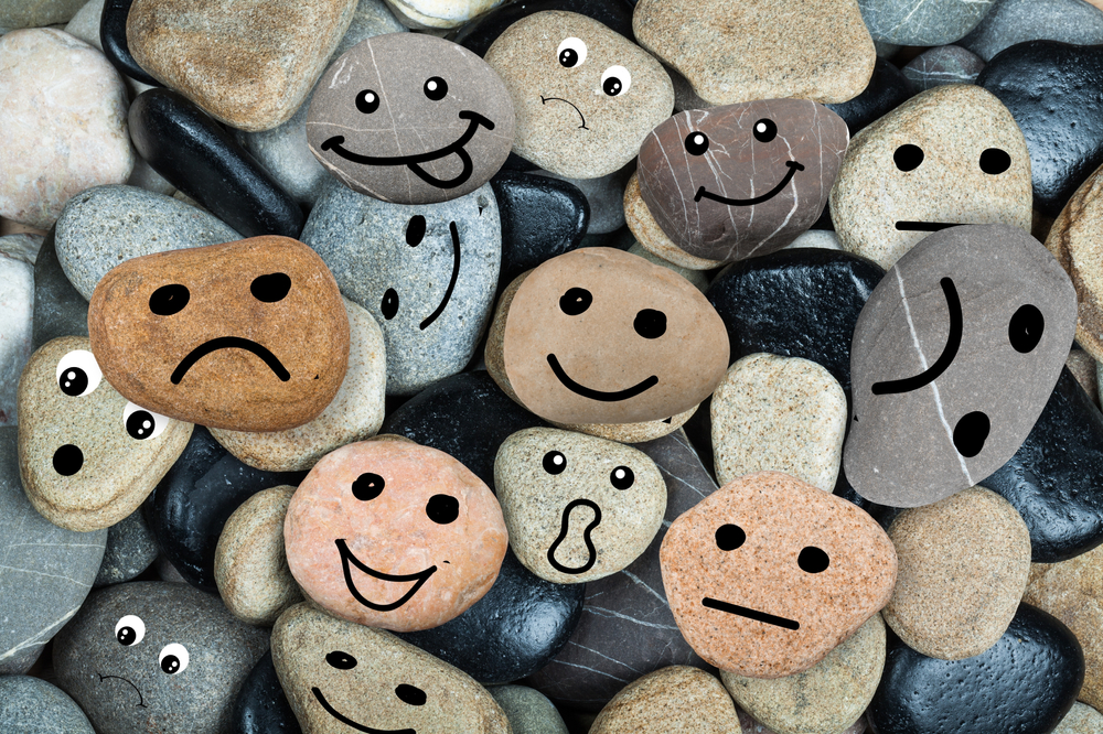 Pebbles with faces drawn on them, showing lots of different emotions