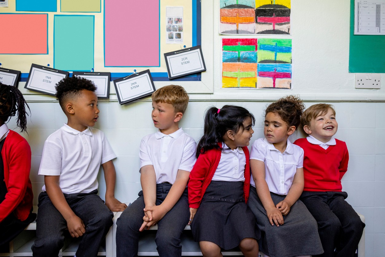 A row of school children sat talking in their uniforms