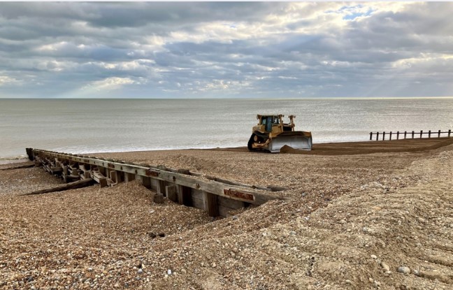 Bulldozer on a shingle beach carrying out shingle reprofiling.