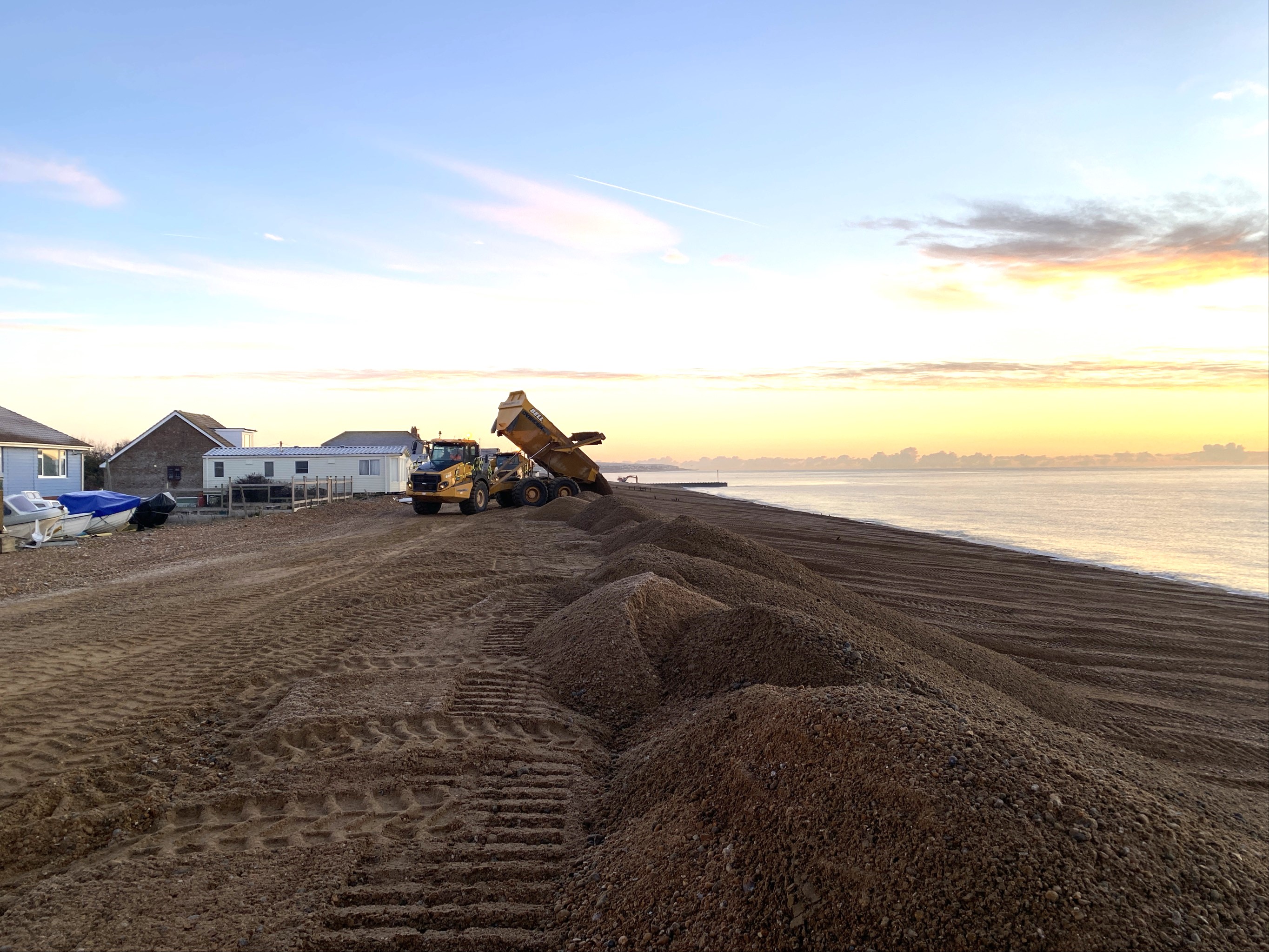 A dumper truck on Pevensey beach moving shingle to reinforce coastal defences.
