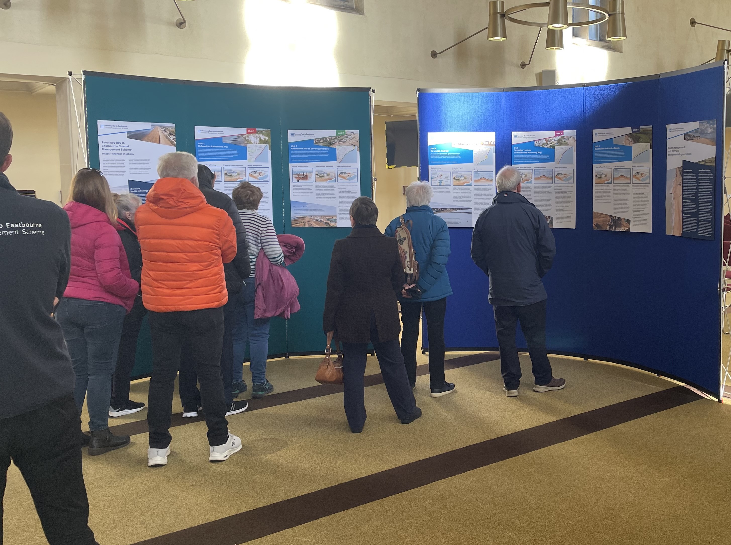 Public engagement event in Eastbourne with several people reading information about the Scheme.
