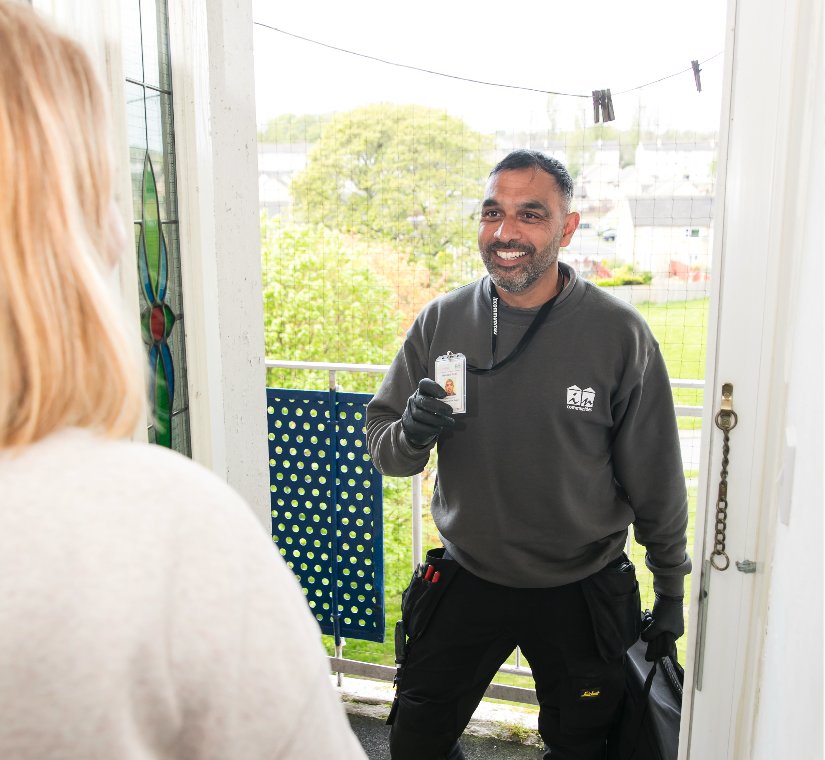 An Incommunities colleague smiling as he chats with a customer at her front door