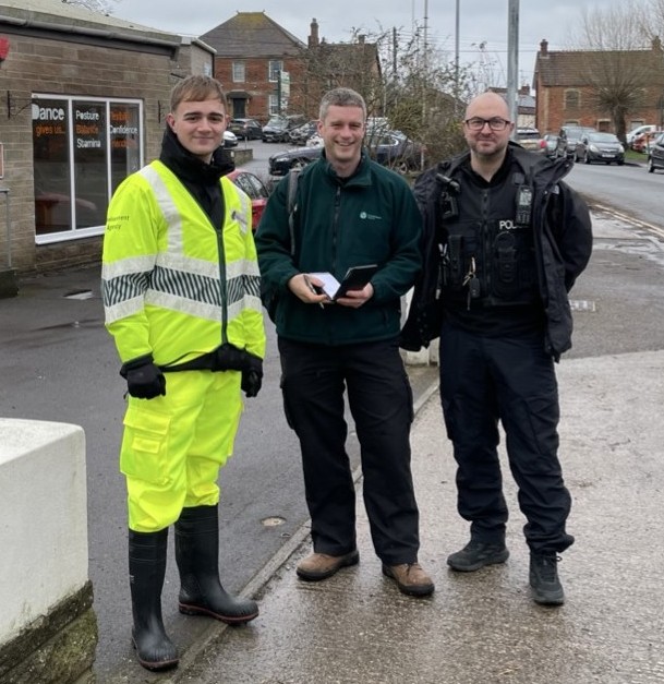 Two Environment Agency Officers and one Police Officer standing by the roadside