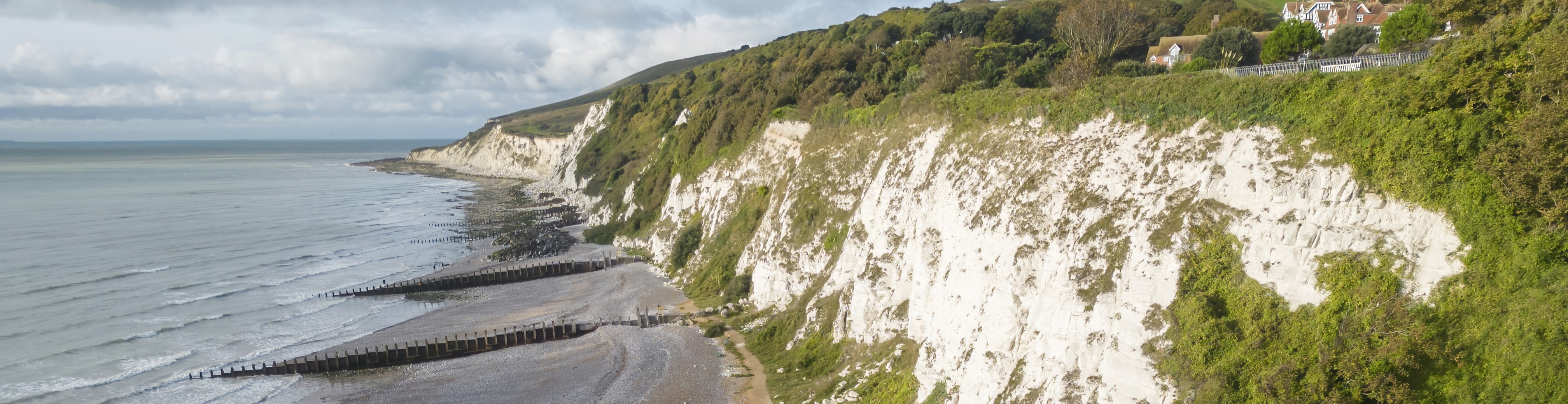 View of the white chalk cliffs at Holywell with the shingle beach and sea below.
