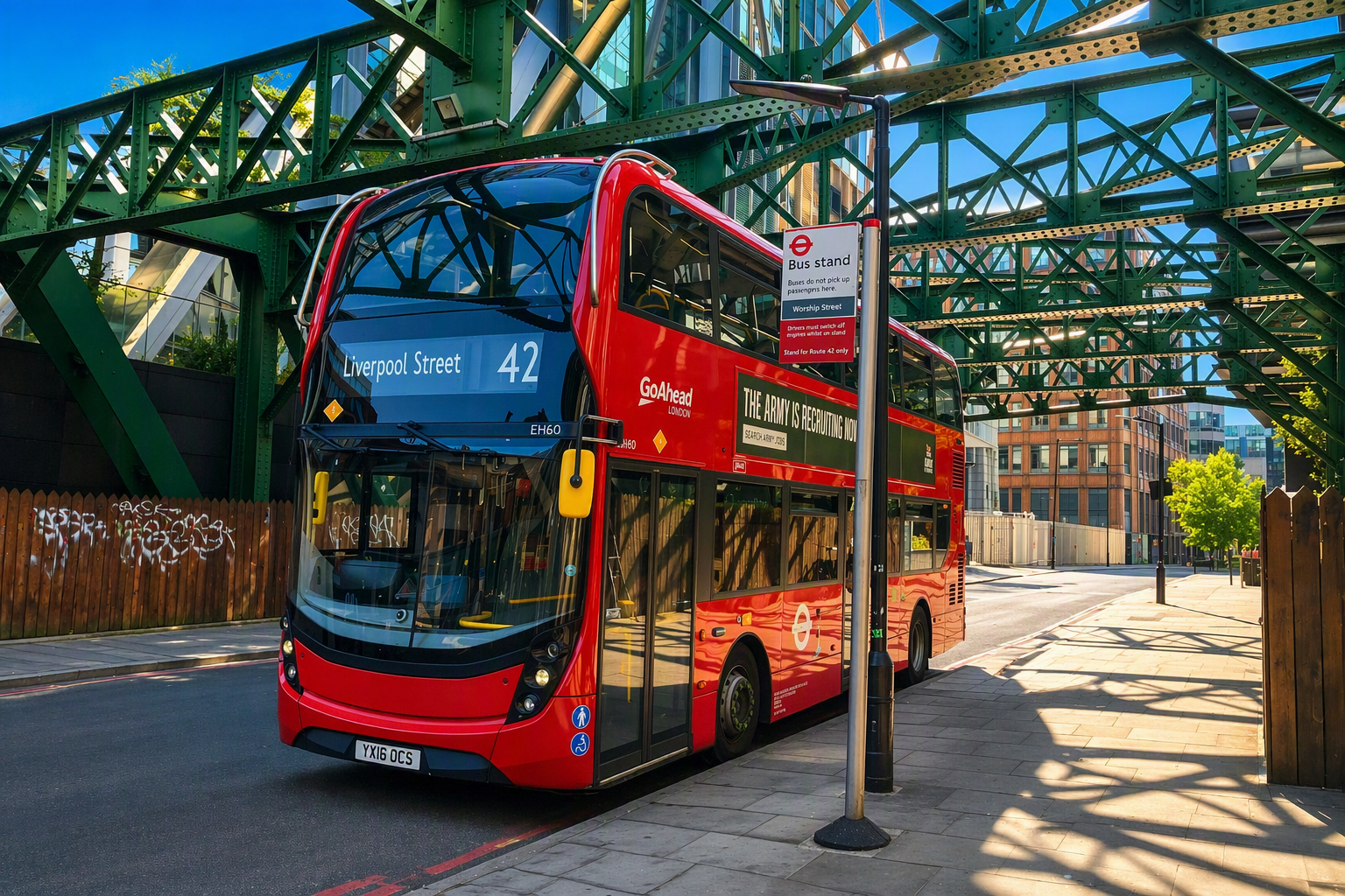 Route 42 double decker bus at a bus stand beneath green steel railway bridges in the City of London