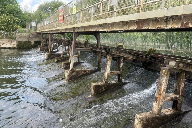 photo showing the small radial weir gates with the walkway above that needs refurbishment