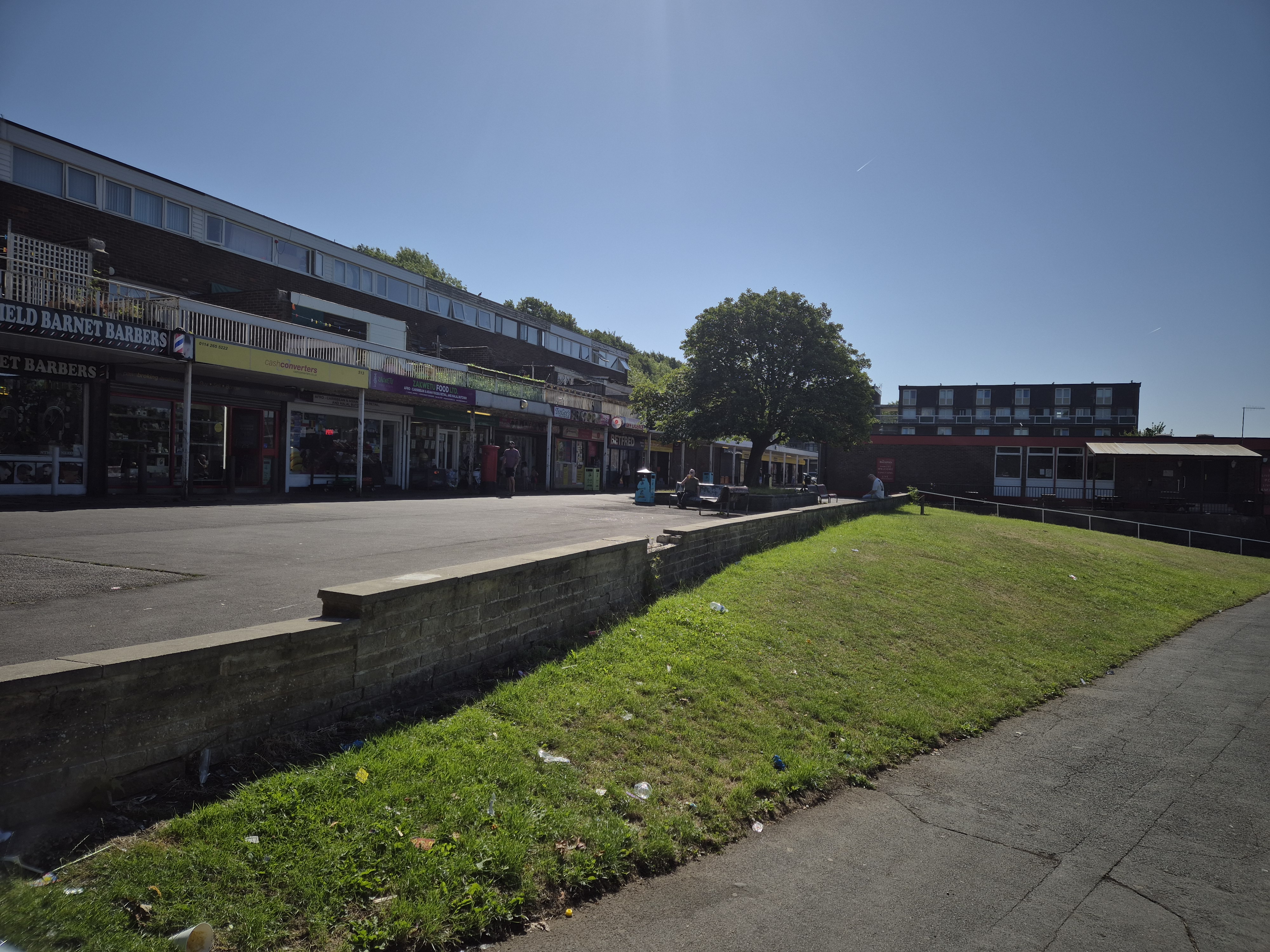 Newfield Green shops, green grass in the foreground and a blue sky