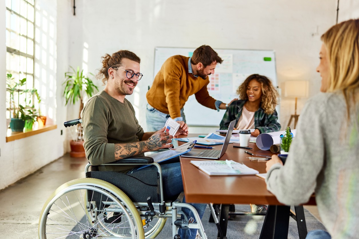A male wheelchair user smiles in a meeting at his first day in a new job