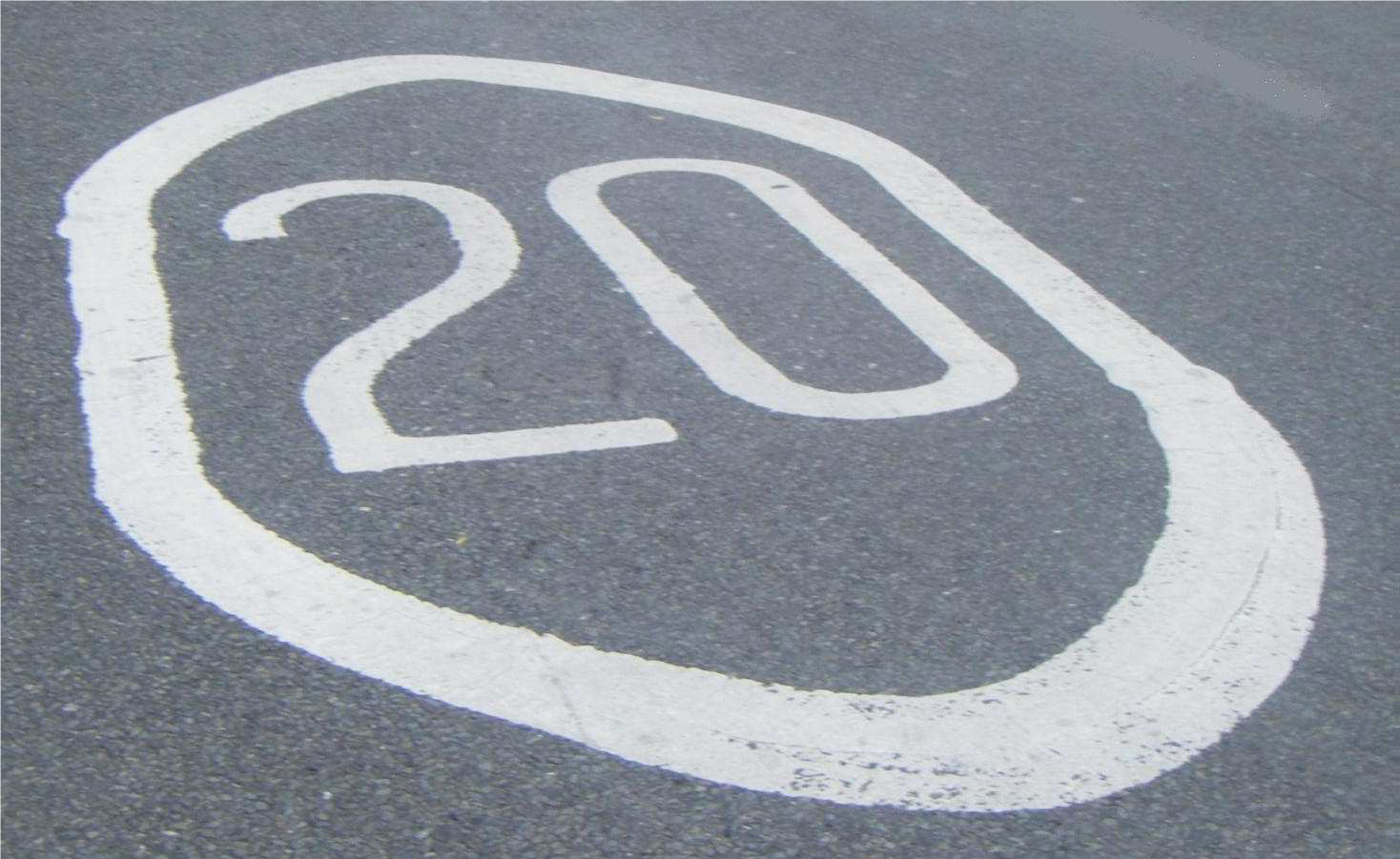 Image of a white road marking of a 20mph speed limit in a white circle on a grey road