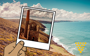 Image of someone holding up a photo of a footpath set in a spectacular coastal landscape