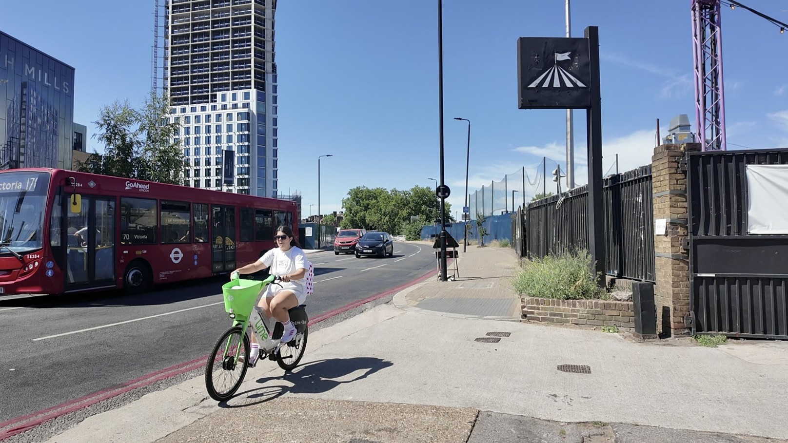 Armour Way with a cyclist riding along a pavement beside bus 170 and cars following behind