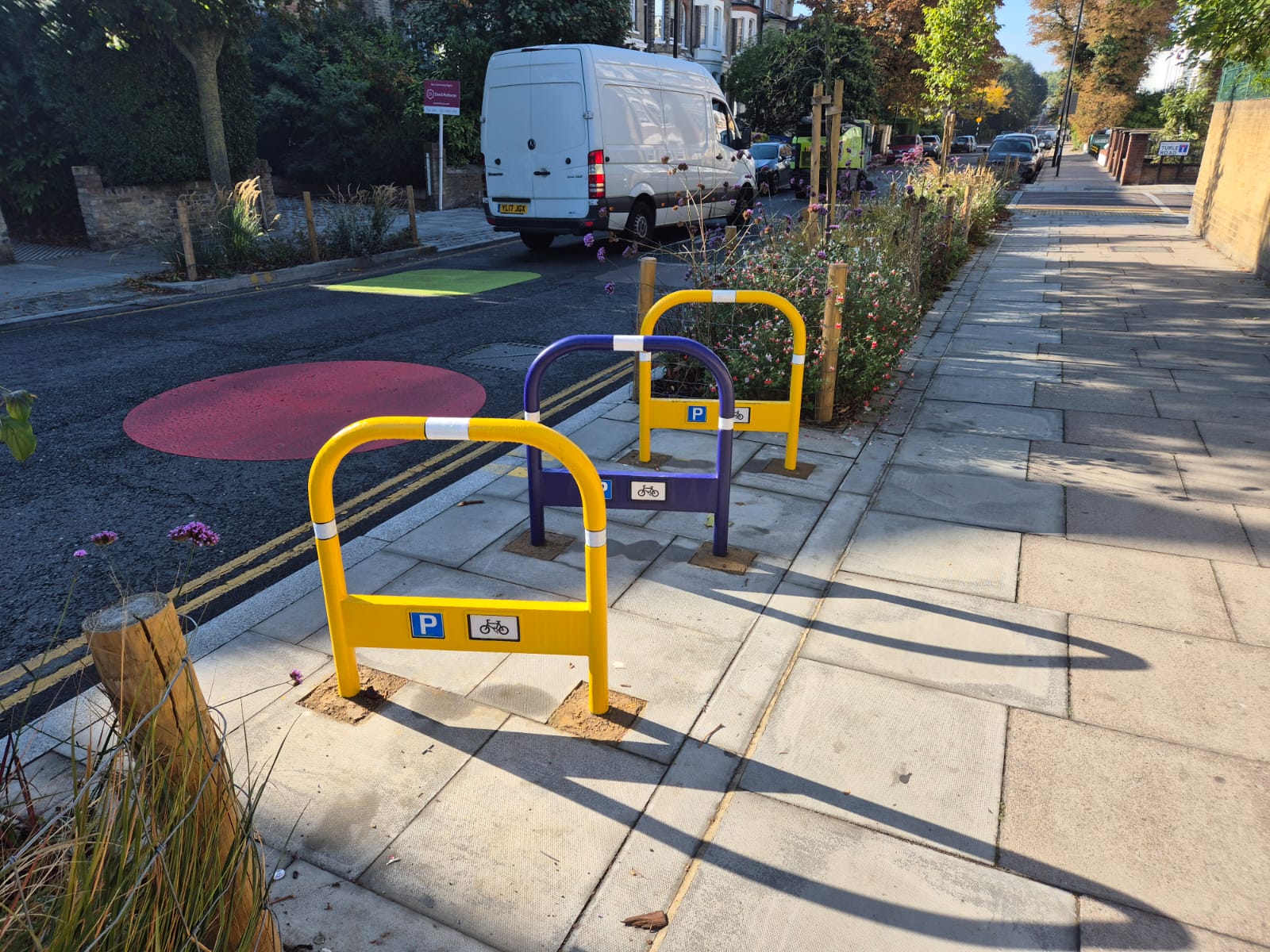 Brightly coloured cycle stands on a pavement outside a school
