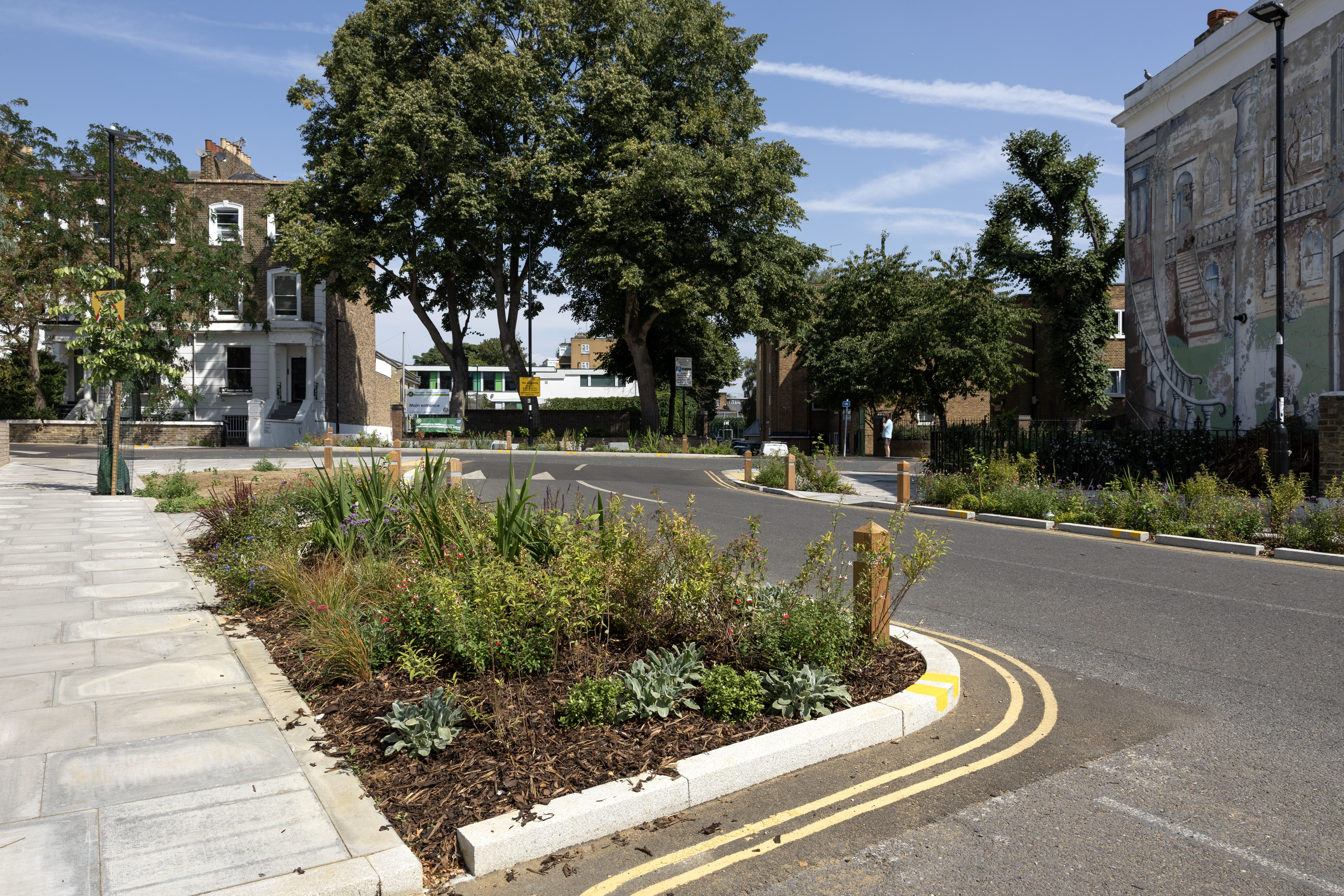 Junction of local streets with road narrowed by wider pavements with planting on