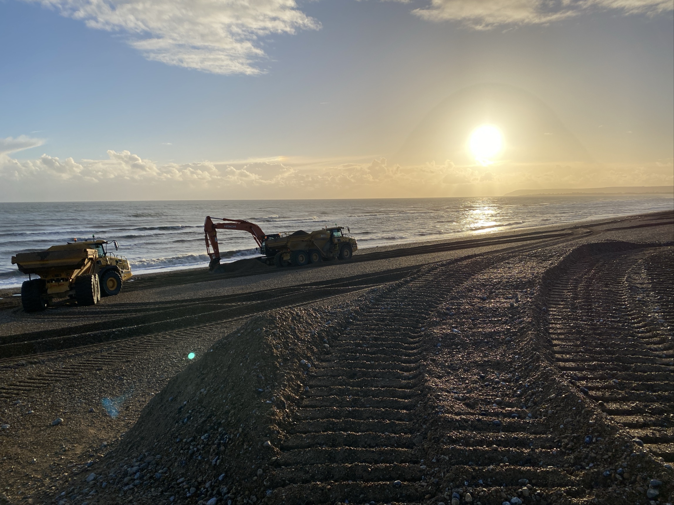 Machinery on Pevensey beach moving shingle to reinforce coastal defences.