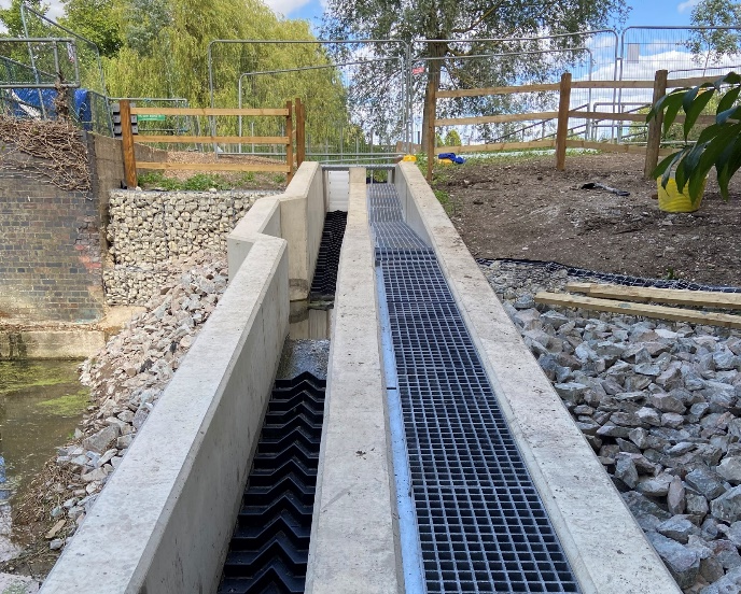 A view of the pass looking upstream, with the fish pass on the left showing the Larinier tiles and the eel pass on the right, covered by a walkway for maintenance access.
