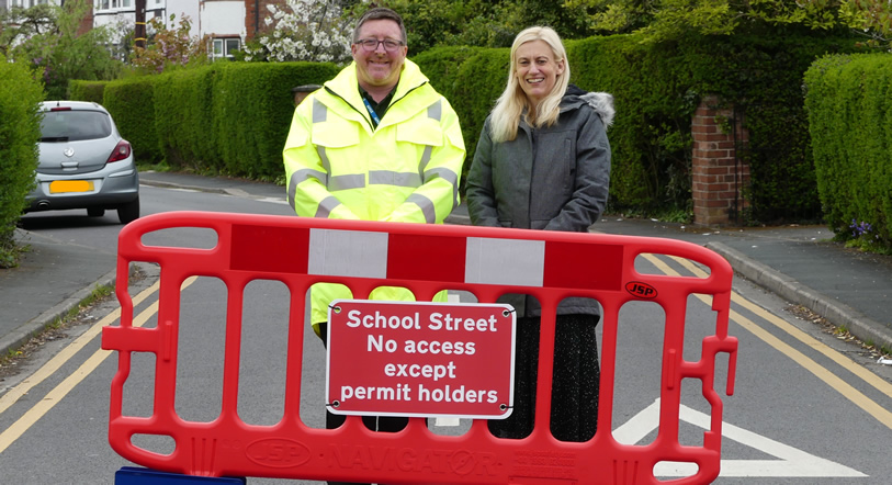 Staff behind barrier with school street sign on