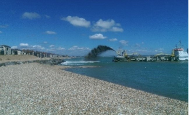 Dredger Sospan Dau spraying a high arc of shingle onto the beach in a process known as ‘rainbowing’