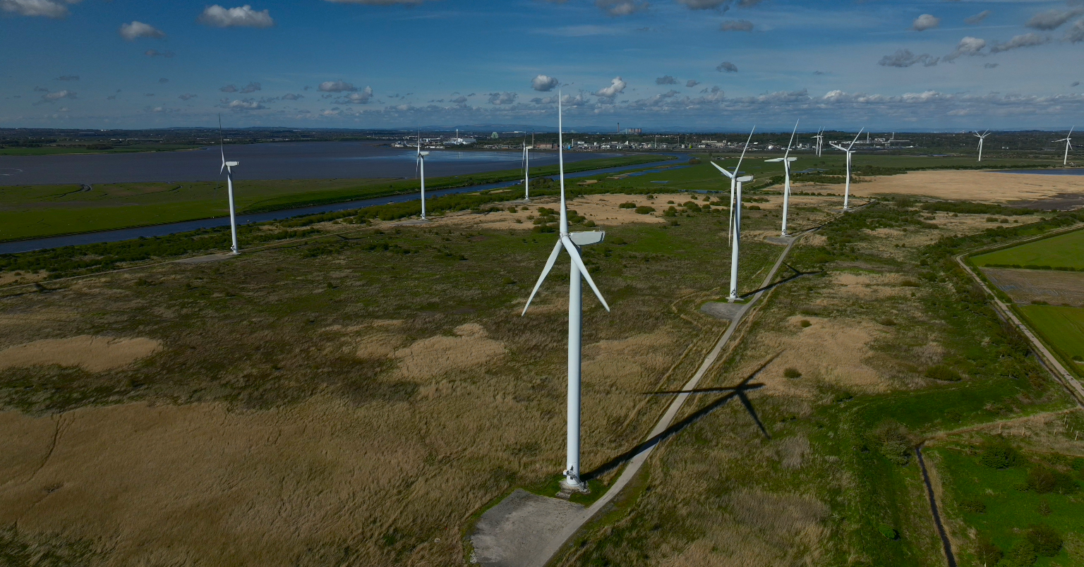 A windfarm with estuary and industry in background