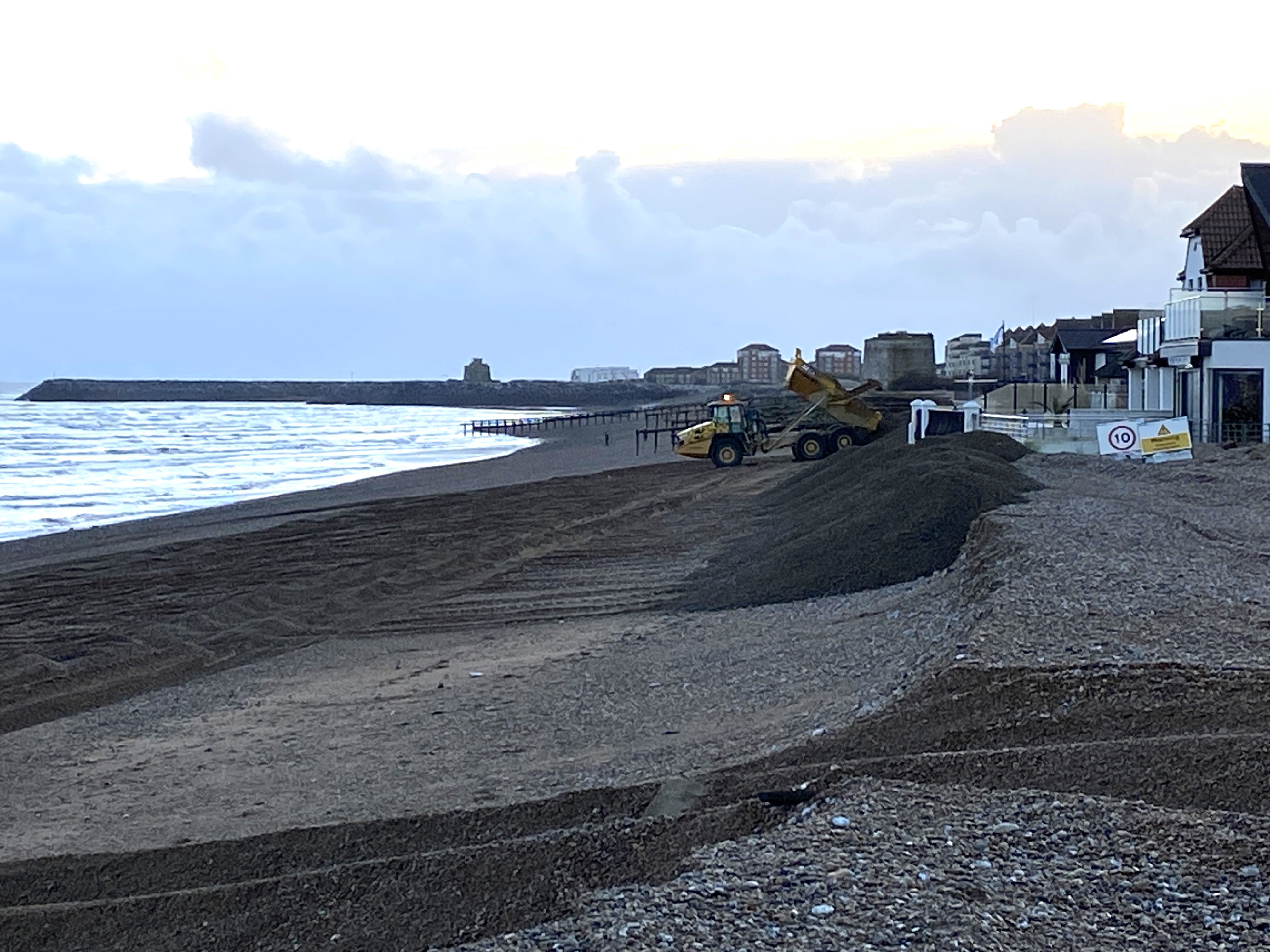 A dumper truck on Pevensey beach moving shingle to reinforce coastal defences.