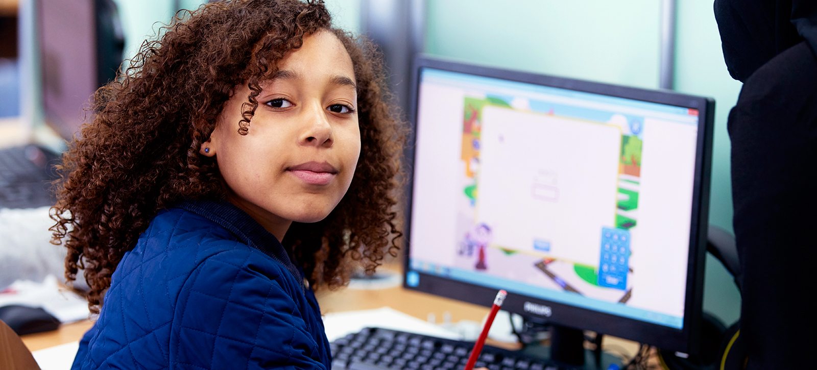 Student smiling whilst working on a computer