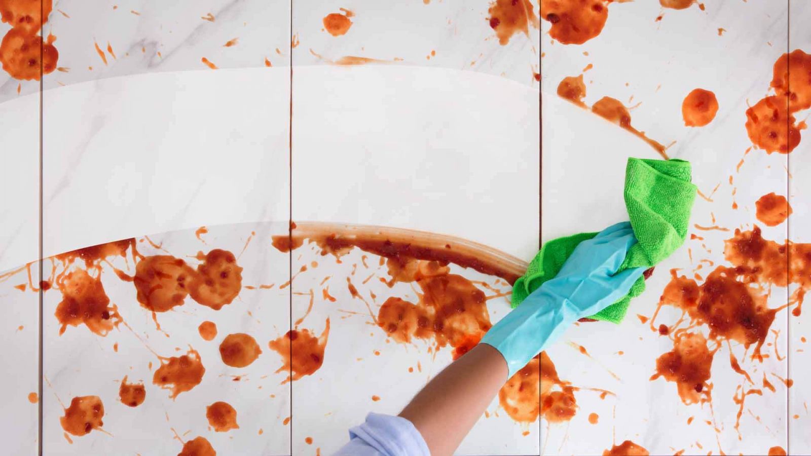 person wiping red splashes from a tile