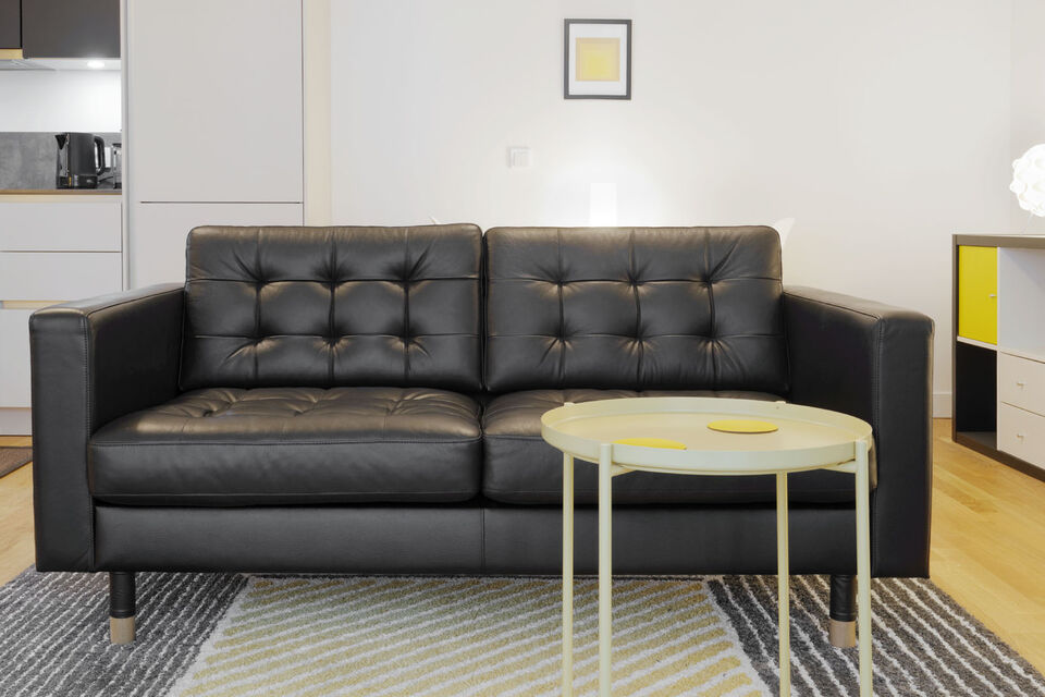 Möblierte Wohnung, Wohnzimmer mit schwarzem Ledersofa in Berlin Mitte