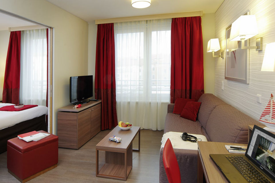 Serviced apartment, bedroom with red velvet armchair in Munich Ludwigsvorstadt