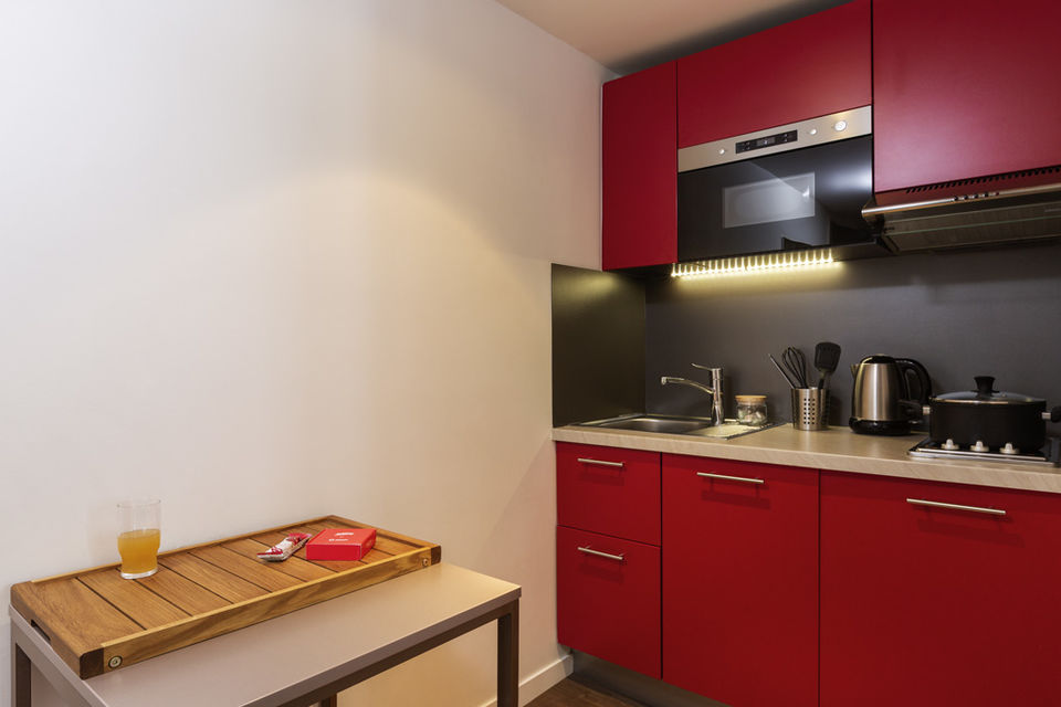 Serviced apartment, kitchen with red fitted kitchen in Munich Ludwigsvorstadt