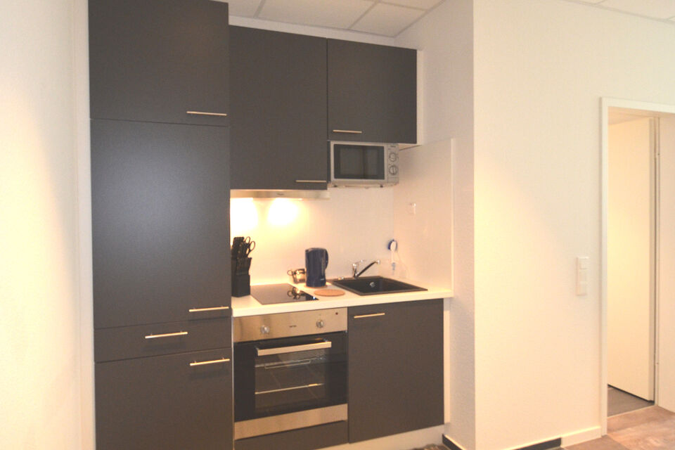 Serviced apartment, kitchen with modern black fitted cabinets in Frankfurt Niederrad