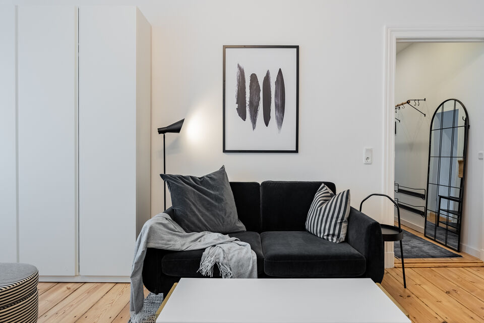 Möblierte Wohnung, Wohnzimmer mit schwarzem Sofa in Berlin Friedrichshain