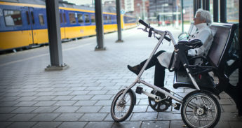Vrouw wacht met vouwfiets op de trein