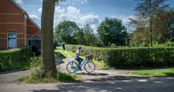 Een meisje fietst op het Groningse platteland
