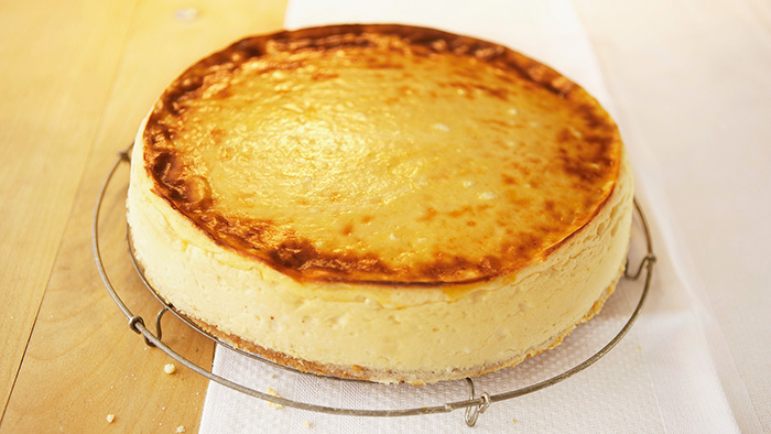 Ein ganzer Käsekuchen mit einer goldgelben Kruste auf eine Gitter / mauritius images / foodcollection