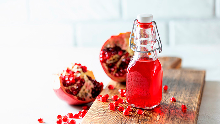 eine kleine Glasflasche mit Granatapfelessig und Granatäpfeln / mauritius images / Gulsina Shaina / Alamy / Alamy Stock Photos