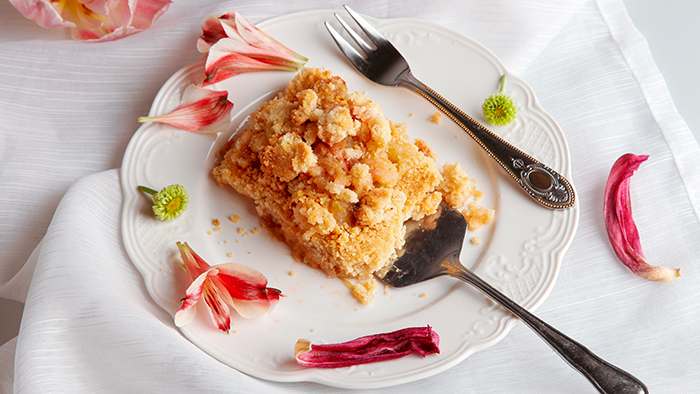 Ein Stück Apfelkuchen mit Streuseln aus der Vogelperspektive fotografiert; der Kuchen wird mit einer Kuchengabel auf einen Kuchenteller geschoben. / mauritius images / Fatma YükselGedeckter Tisch mit Brotzeit