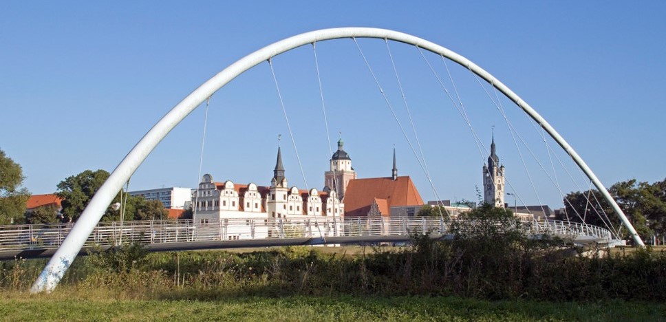 Weißer Brückenbogen mit einem Stadtpanorama im Hintergrund. ©Stadt Dessau-Roßlau 