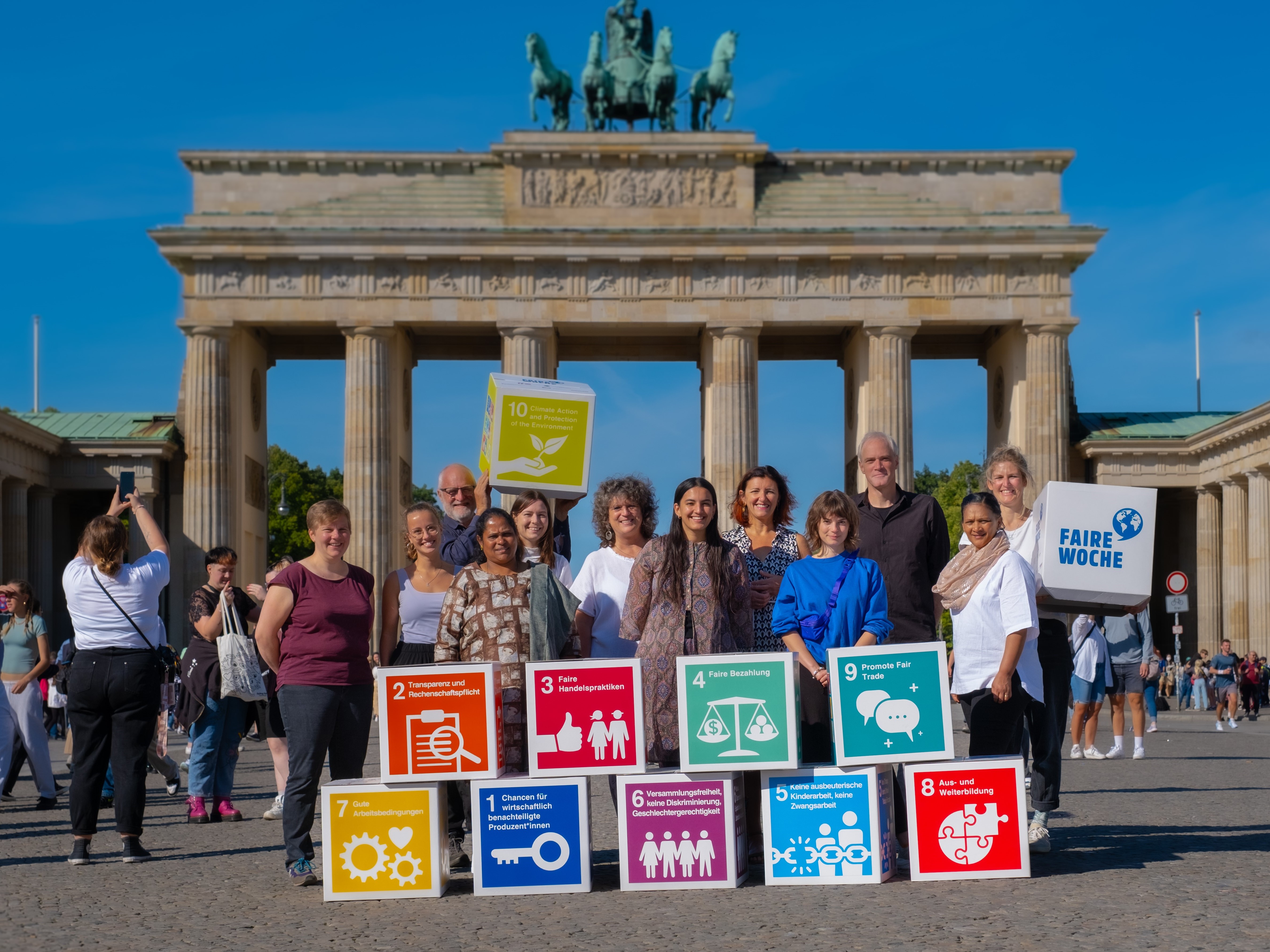 Einige Menschen halten bunte Schilder mit Nachhaltigkeitszielen in den Händen. ©Forum Fairer Handel / Carl Schwarz