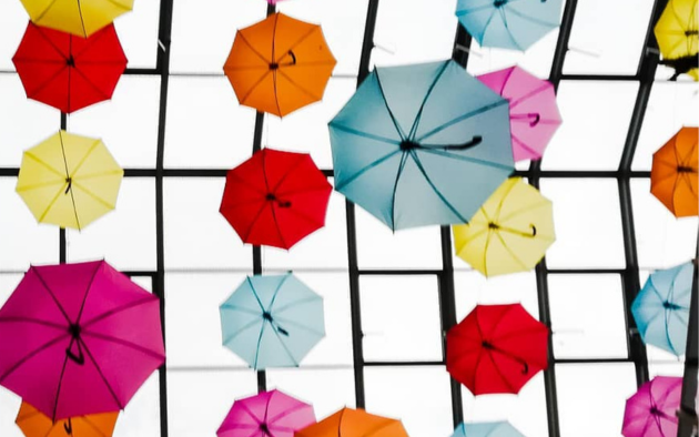 Viele bunte Schirme hängen von einem Glasdach. © Svenja Quitsch