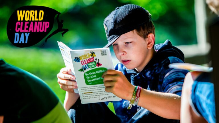 Junge hält eine Klimafibel in den Händen und liest interessiert.