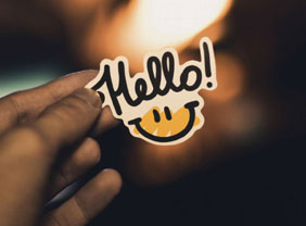 Hand hält einen Sticker mit Smiley und "Hello!"