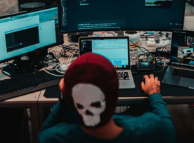 Junger Mann mit Beanie arbeitet an mehreren Monitoren