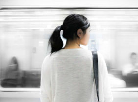 Junge, asiatische Frau steht vor einer abfahrenden U-Bahn