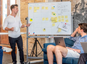 Junger Mann steht vor einem Whiteboard und erklärt etwas